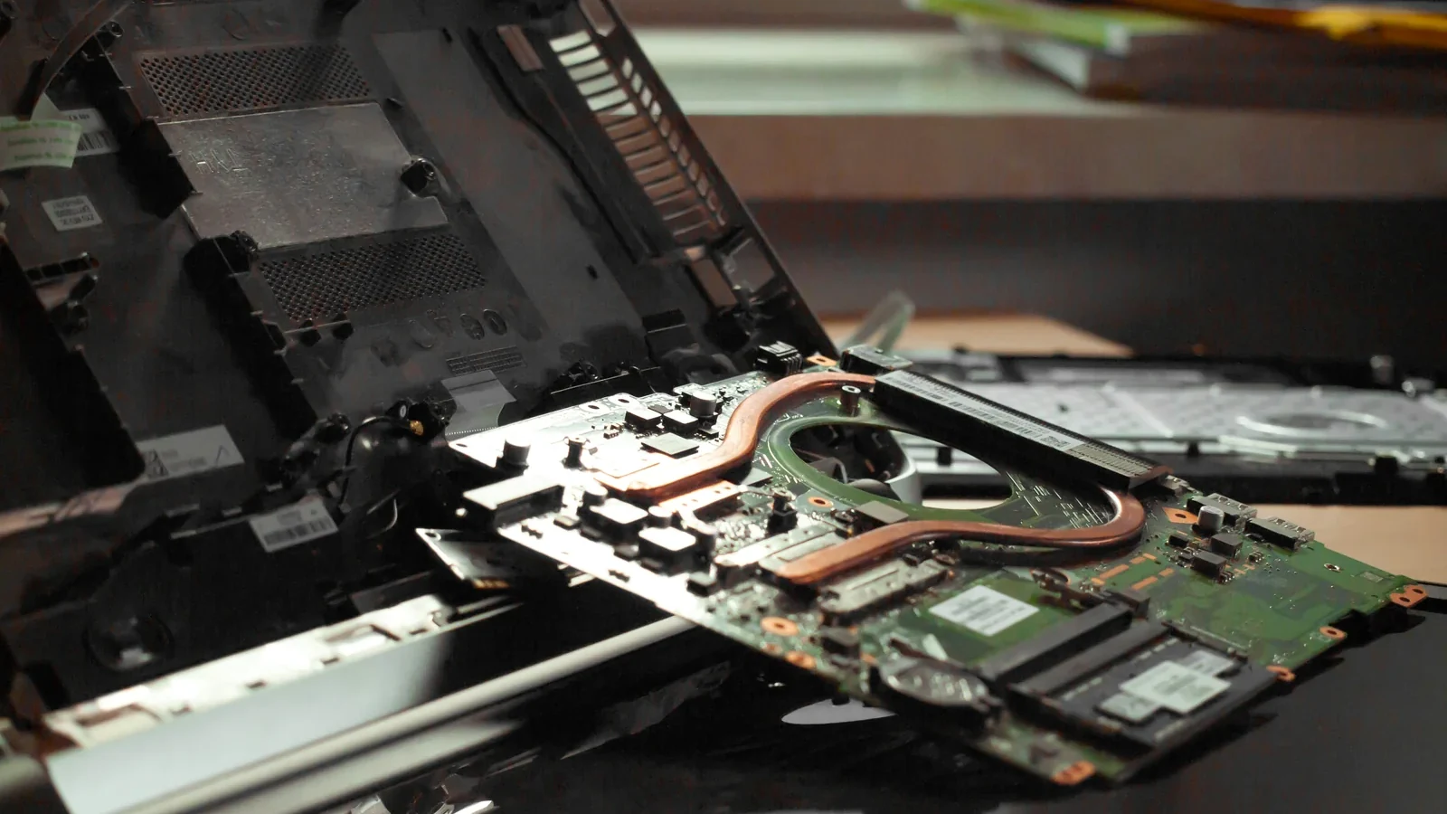Geöffneter Computer in einer Werkstatt mit Werkzeugen und sichtbaren Bauteilen