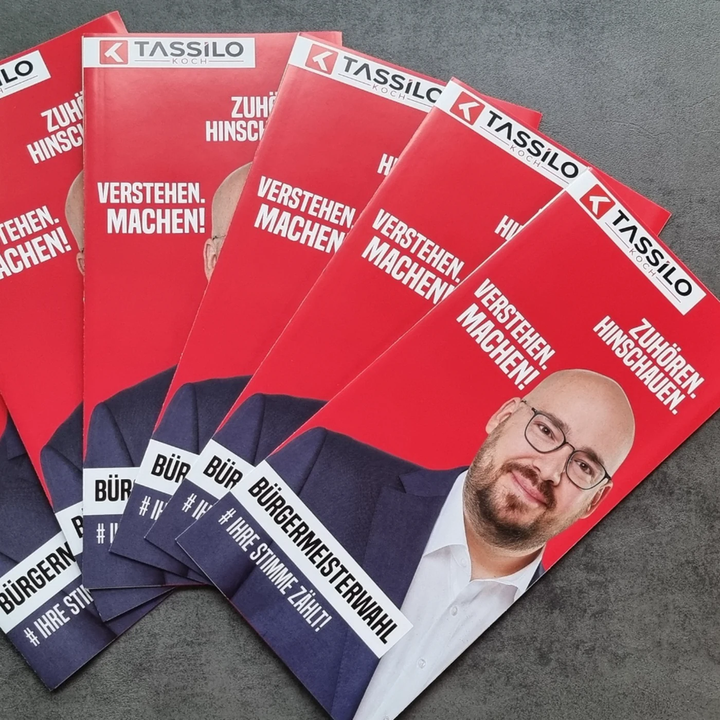 Mehrere rote Wahlkampfflyer mit Porträt und den Aussagen Zuhören, Hinschauen, Verstehen und Machen